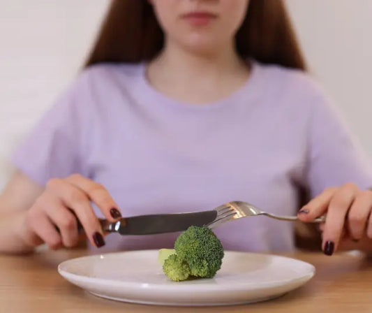 Broccoli sprouts and a scoop of green broccoli sprout powder beside an unbranded supplement jar on a bright kitchen bench.