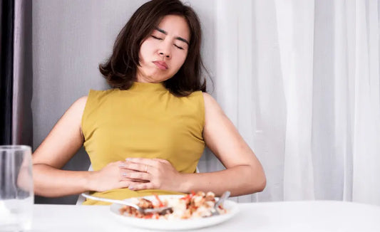 Person after a meal with still water and fresh green and gold kiwifruit, illustrating how to reduce bloating after eating